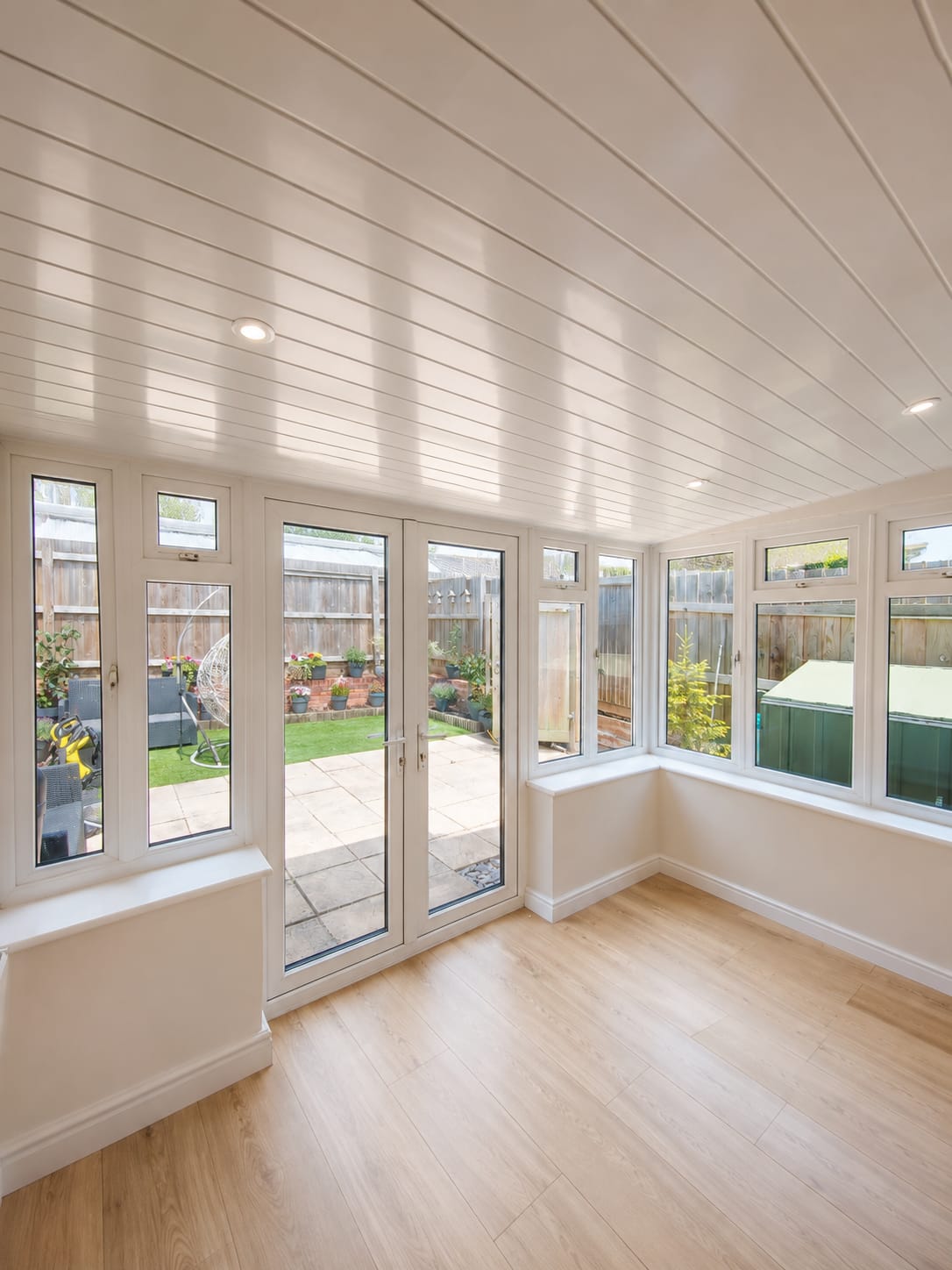 Conservatory project: finished interior with white UPVC French doors and panelled ceiling