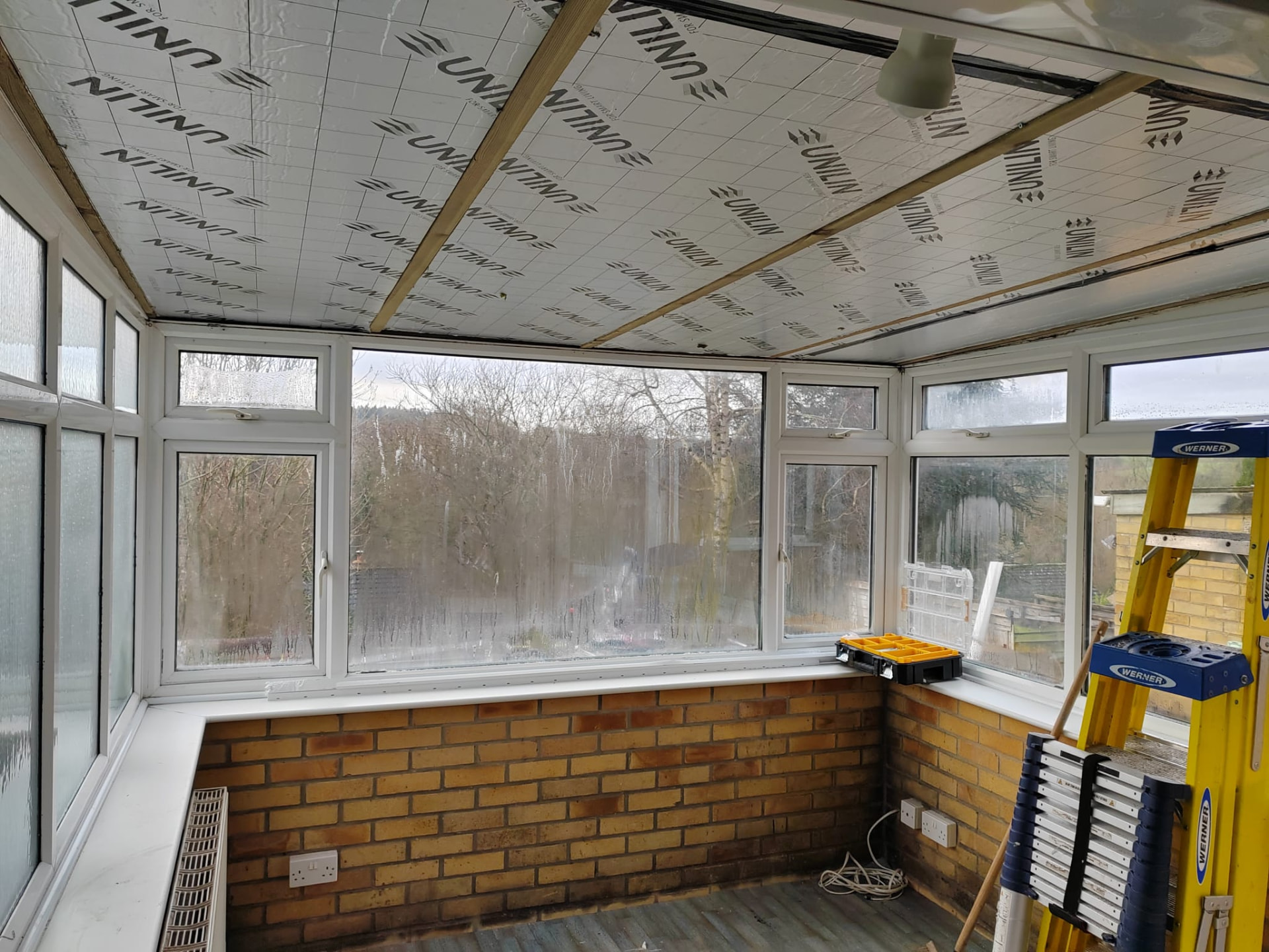Conservatory roof replacement: insulation boards fixed between new timber roof rafters inside the conservatory