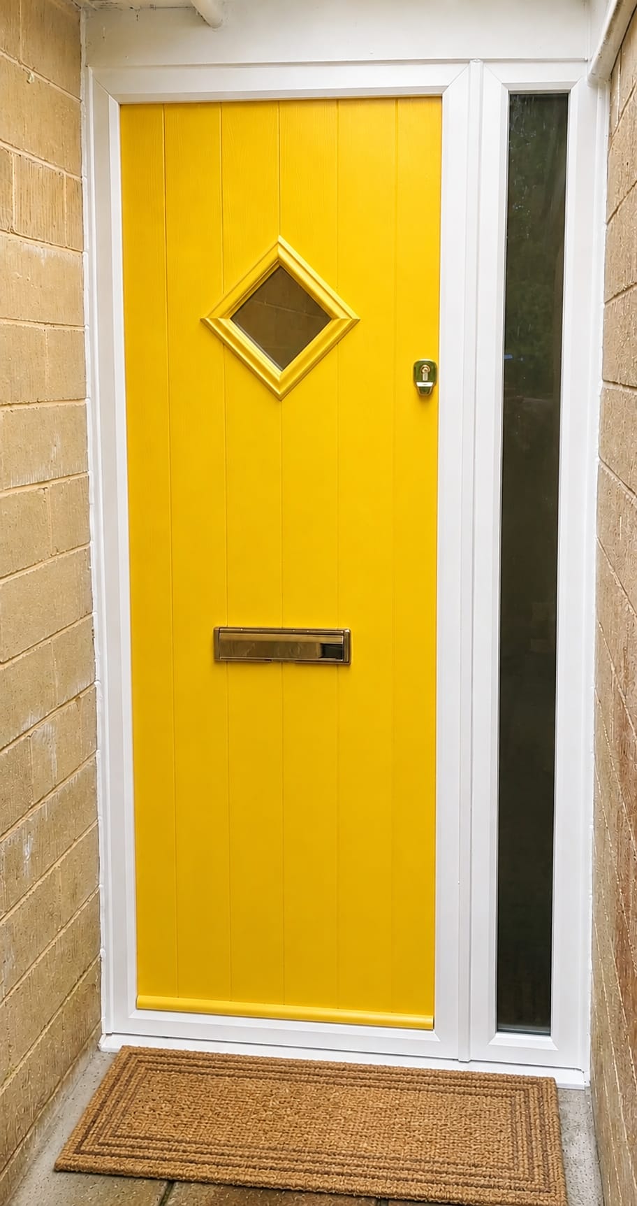 Bright yellow composite front door with diamond glazed panel and brass letter plate