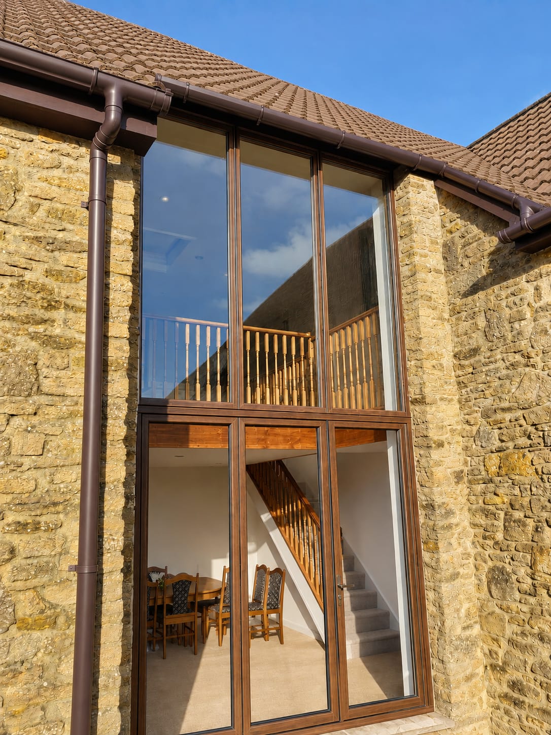 Tall bespoke brown aluminium windows and doors on a stone farmhouse