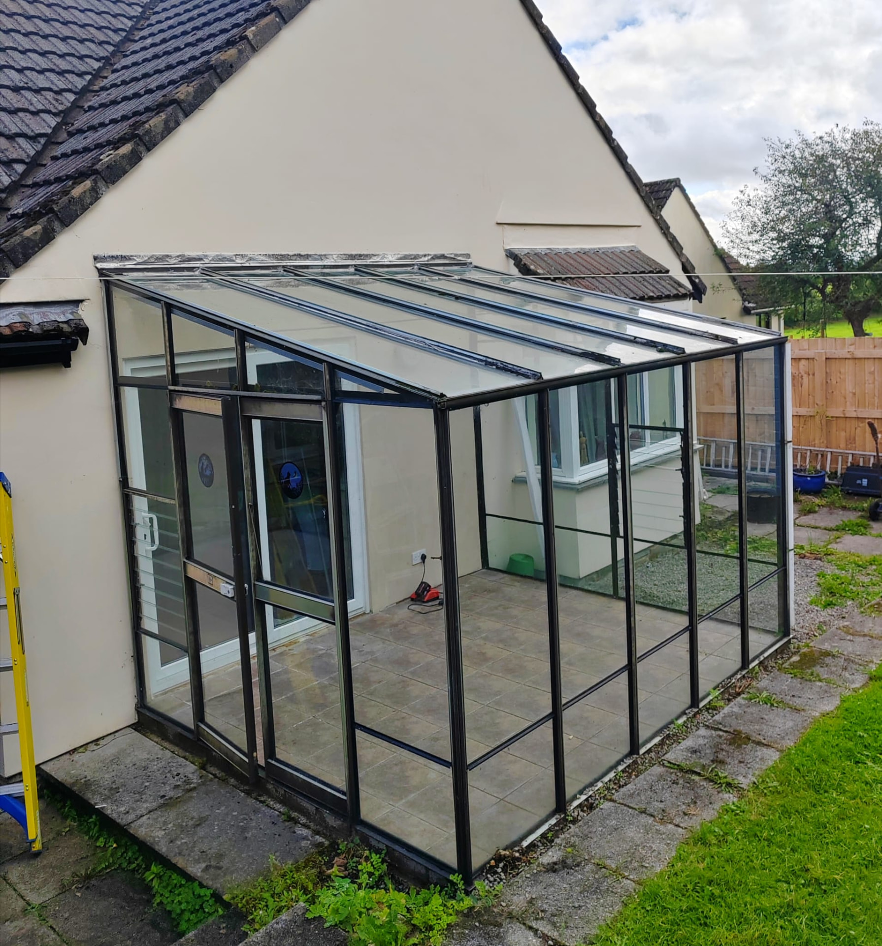 Sunroom project before: tired old black aluminium framed lean-to sunroom on a bungalow