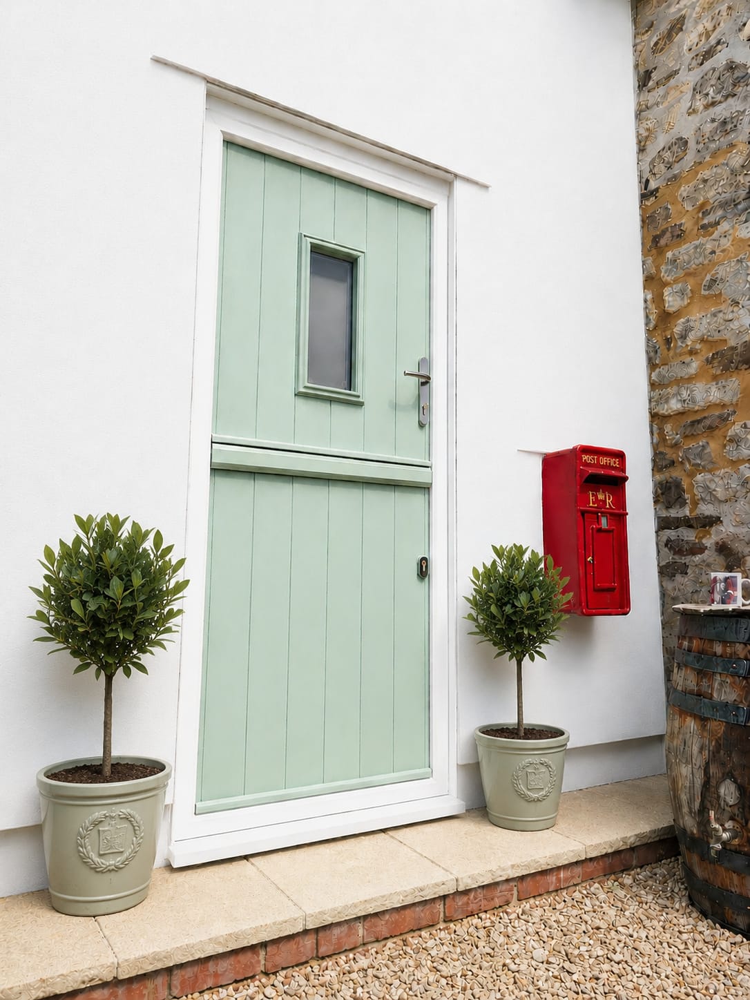 Chartwell green composite stable door with small glazed panel on a white rendered wall