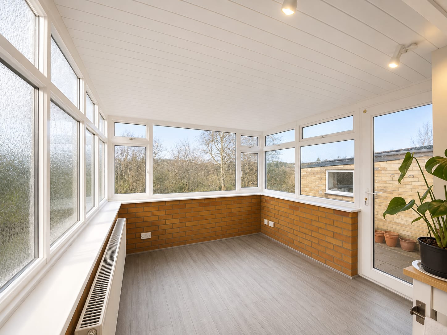 Conservatory roof replacement after: bright interior with new clad and insulated ceiling, white UPVC windows and door onto the patio