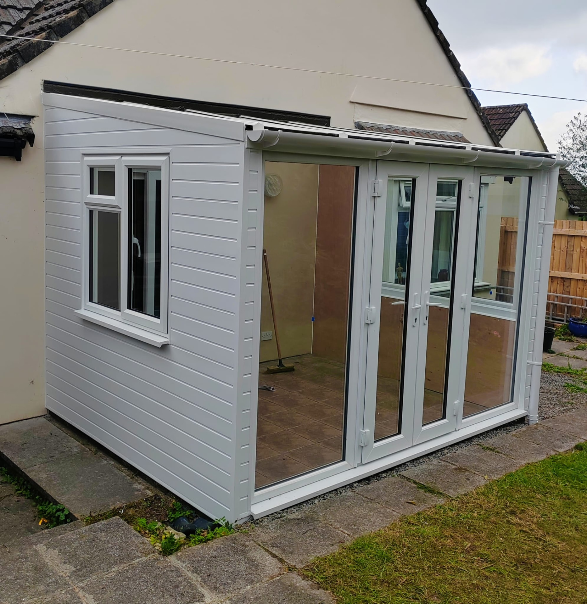 Sunroom project after: finished white UPVC sunroom with side casement window and French doors