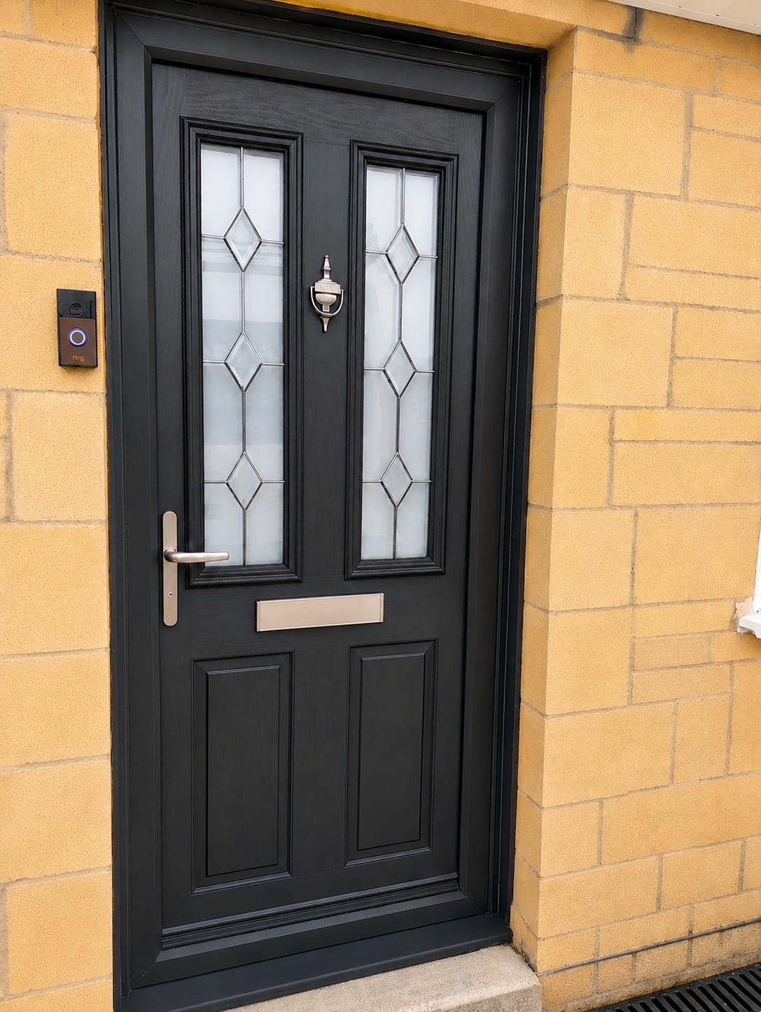Black composite front door with diamond leaded glazing and brushed chrome letter plate on Bath stone