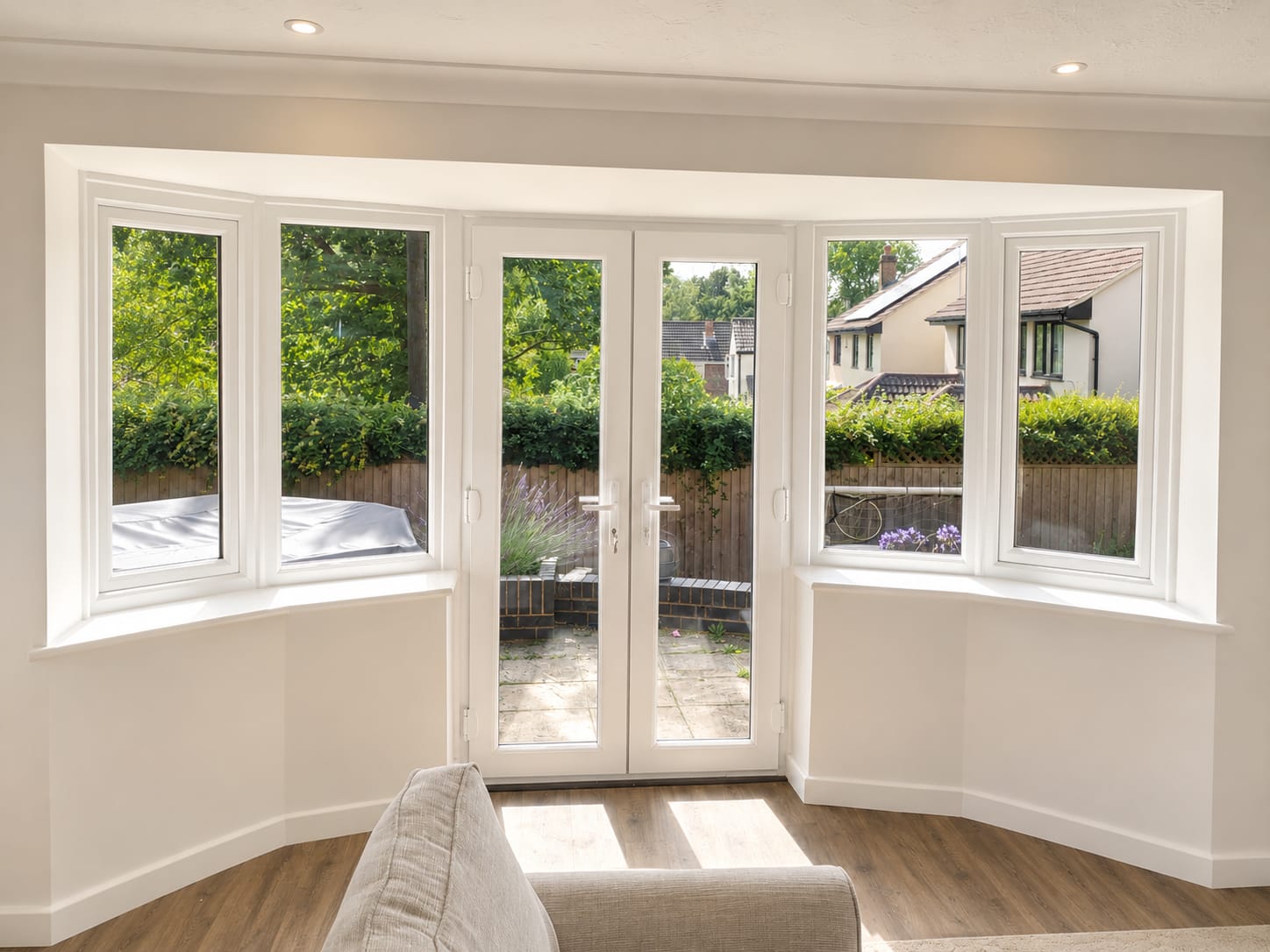 White UPVC French doors with matching side windows opening onto a garden patio