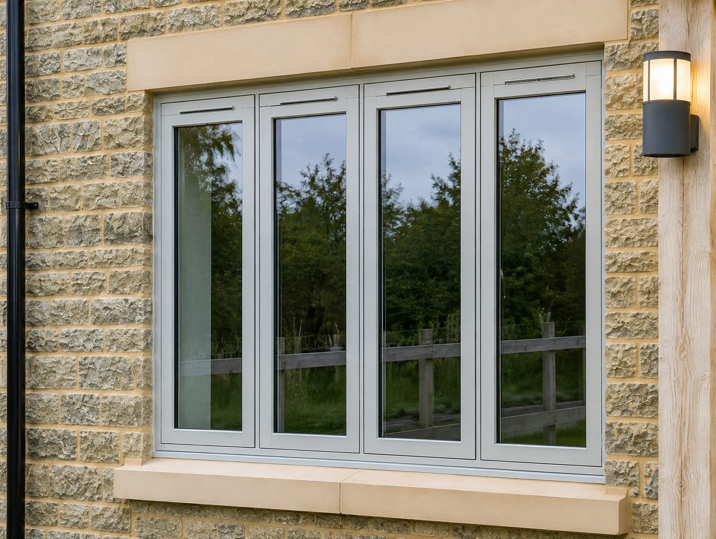Four-pane agate grey flush casement windows in a natural stone new build